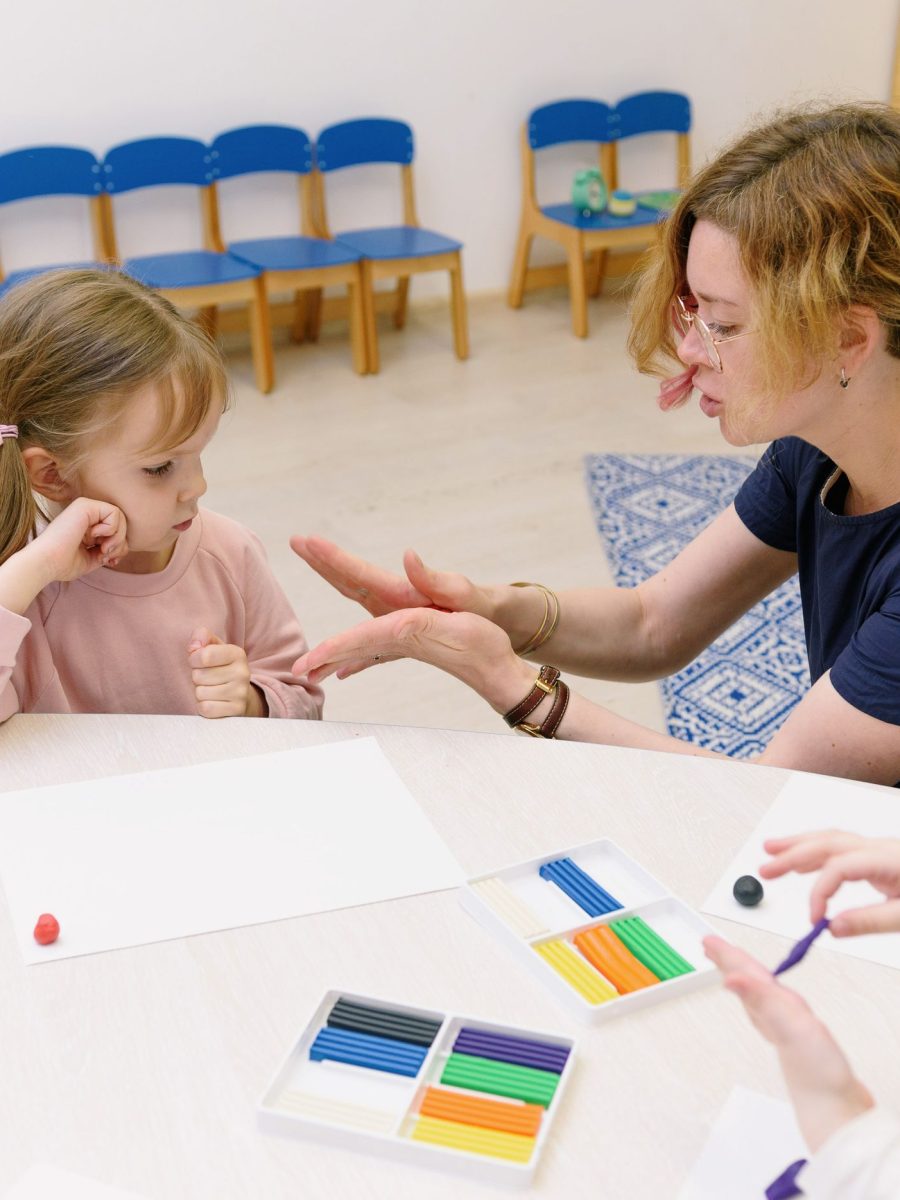 Logopädin übt Aussprache mit einem Mädchen am Tisch